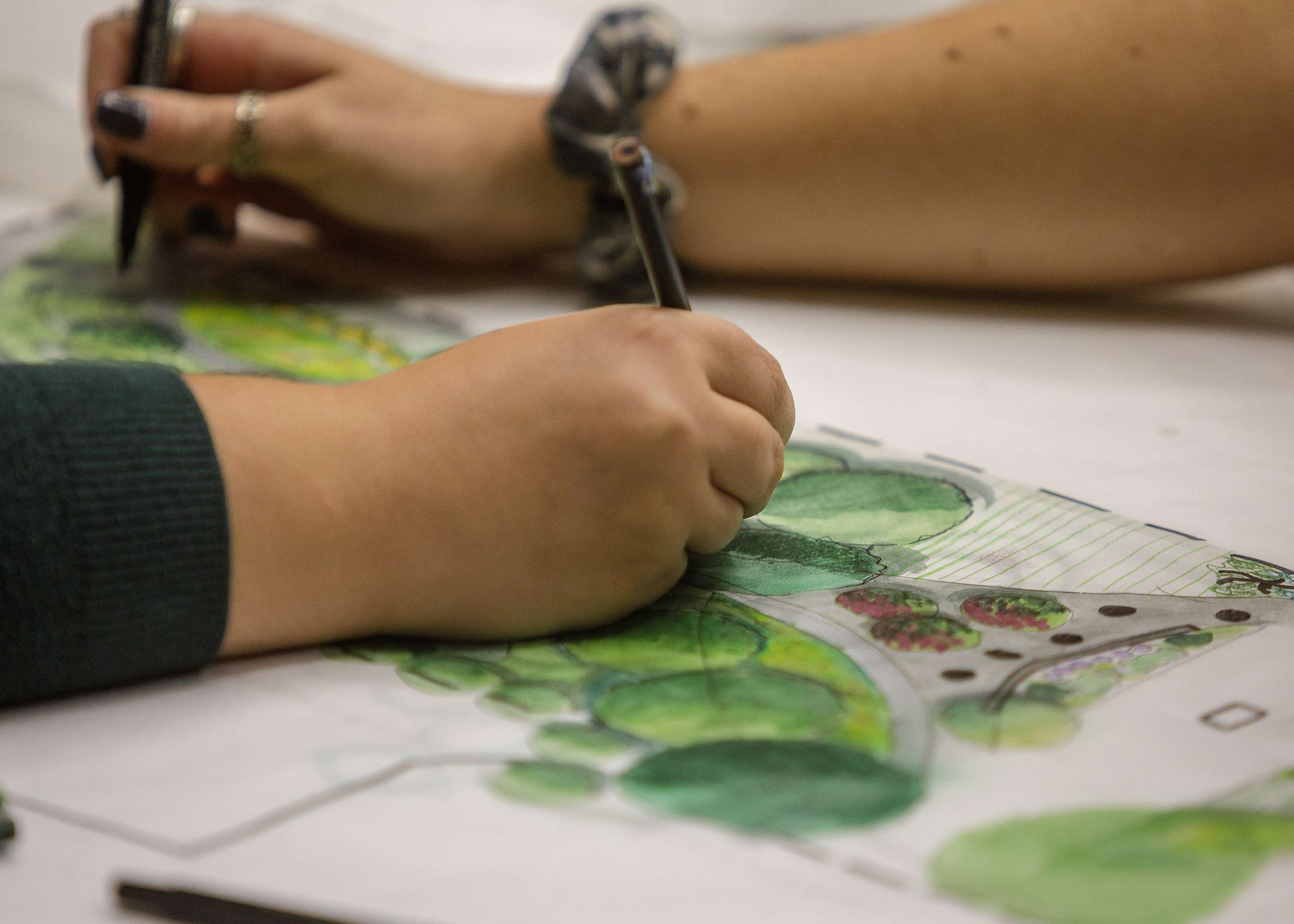 close up photograph of two student hands working on coloring their graphics.