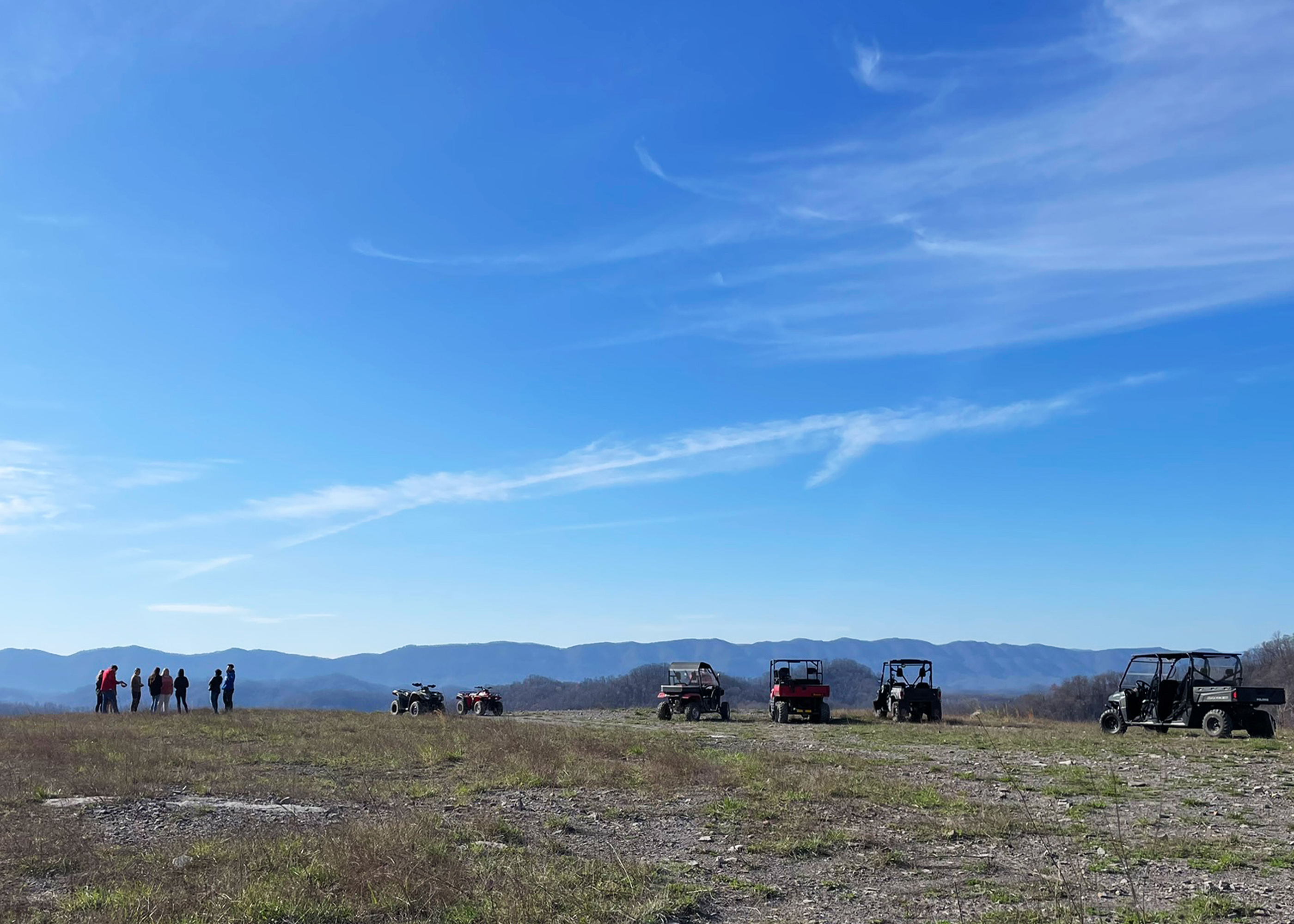 Photograph of students and ATVs on top of mountain around Fleming Neon