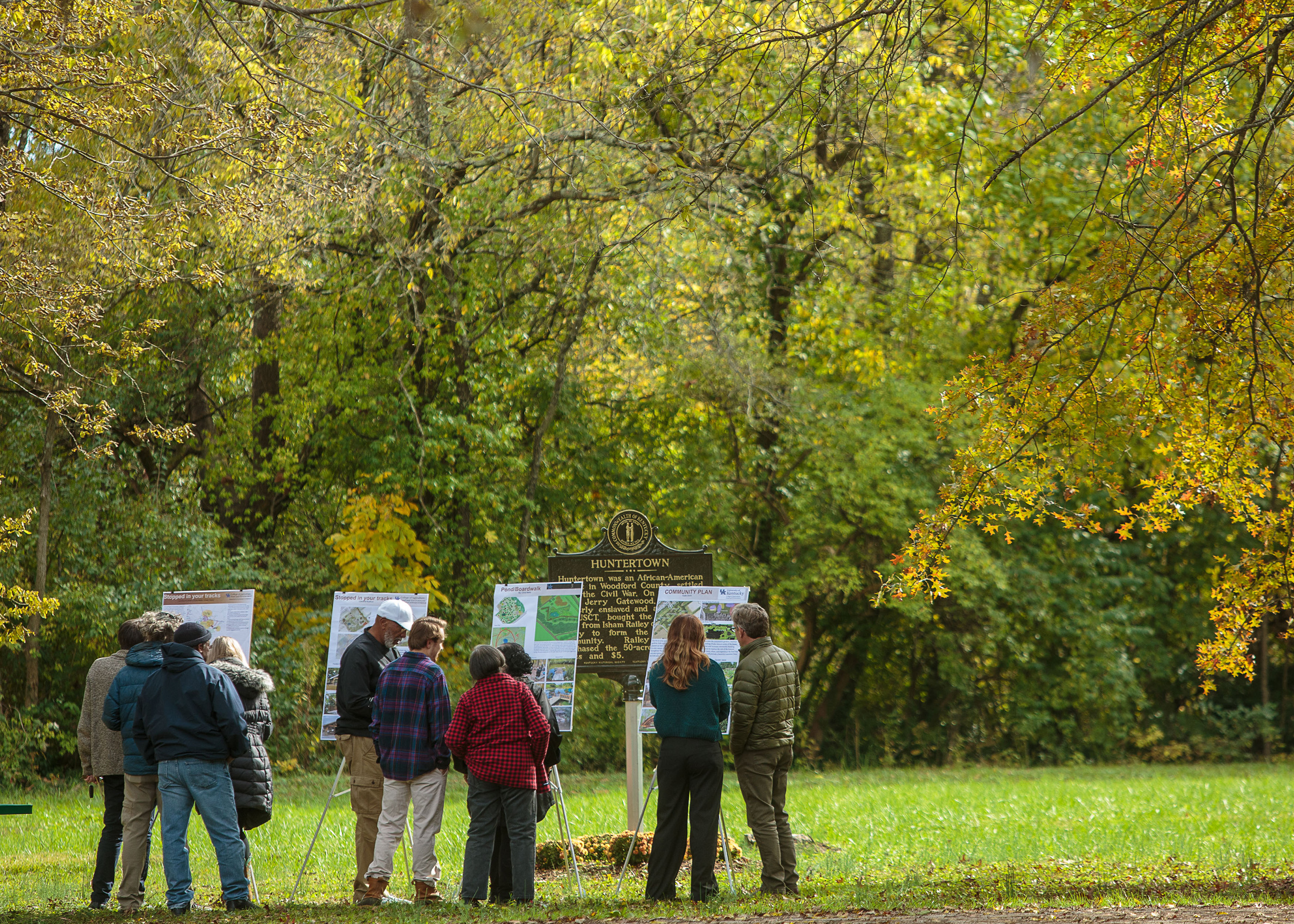 students standing outdoors with community members looking at their posters.