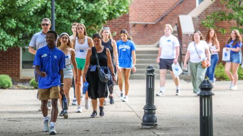 A tour guide walks outside William T. Young Library in the summer